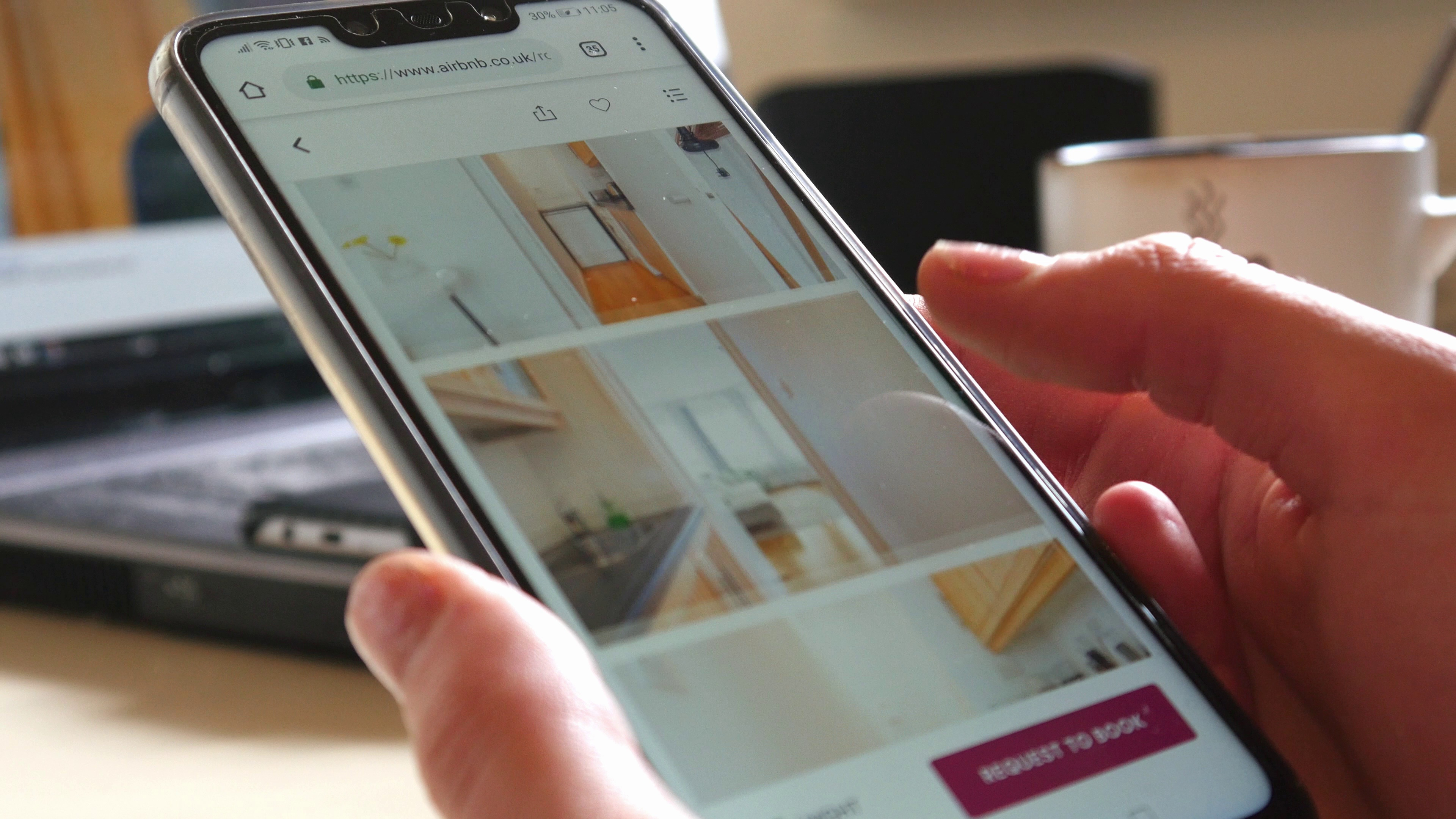woman-trying-to-book-home-apartment-in-london-on-airbnb-app-with-mobile-phone